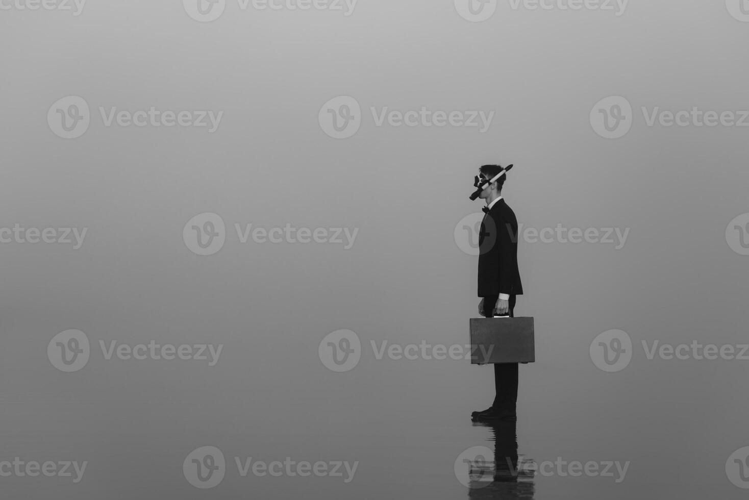 surreal portrait of a man in a suit and mask with a diving tube with a briefcase in his hands standing on the water photo