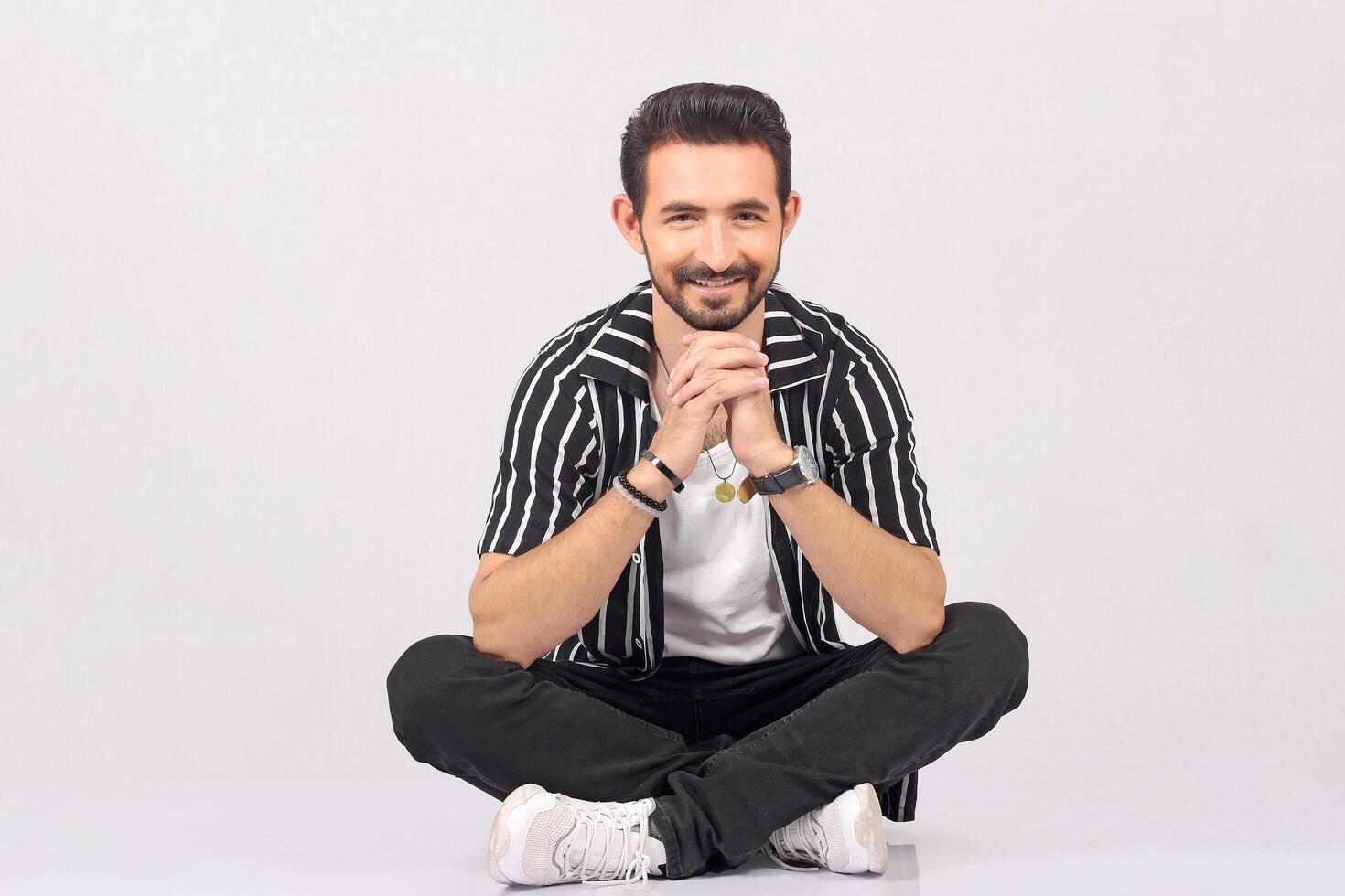 Portrait of a young stylish male model in black shirt and jeans with smile full height and sitting studio shots photo