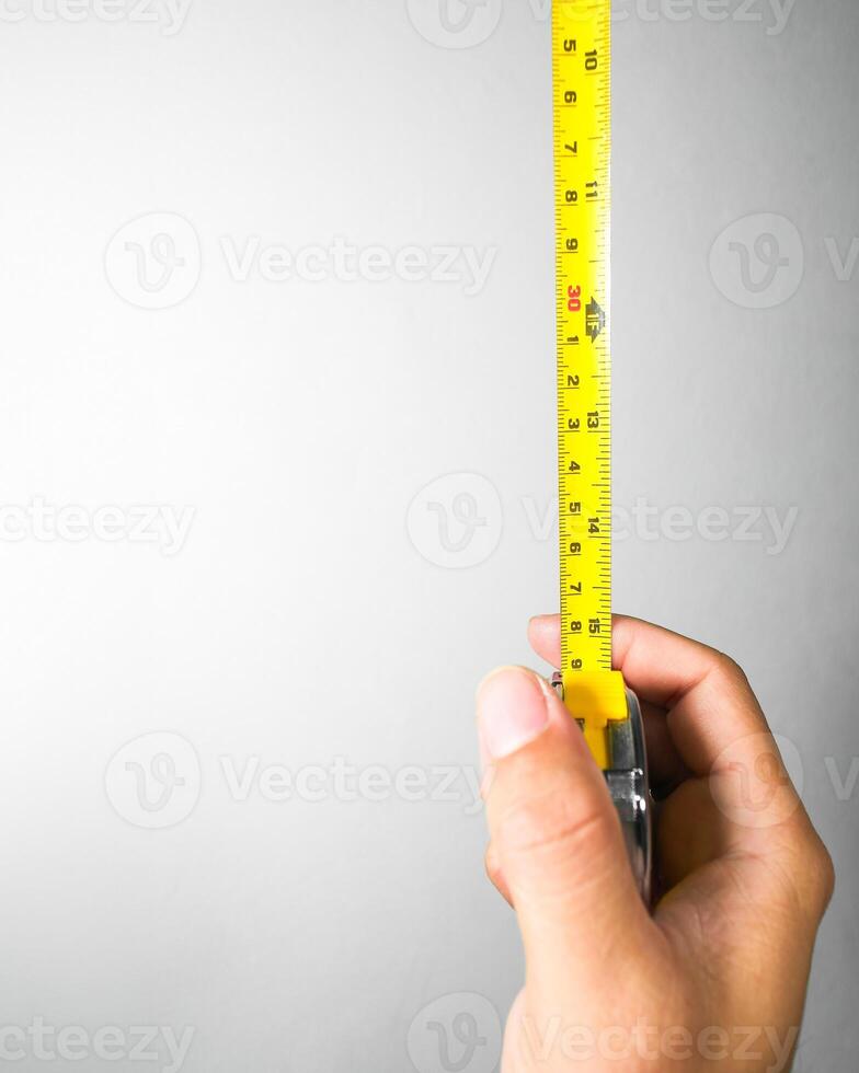 Metal measuring tape in hand with vertical copy space , Metal measuring tape with units of centimeters and inches , Mechanic tools concept photo