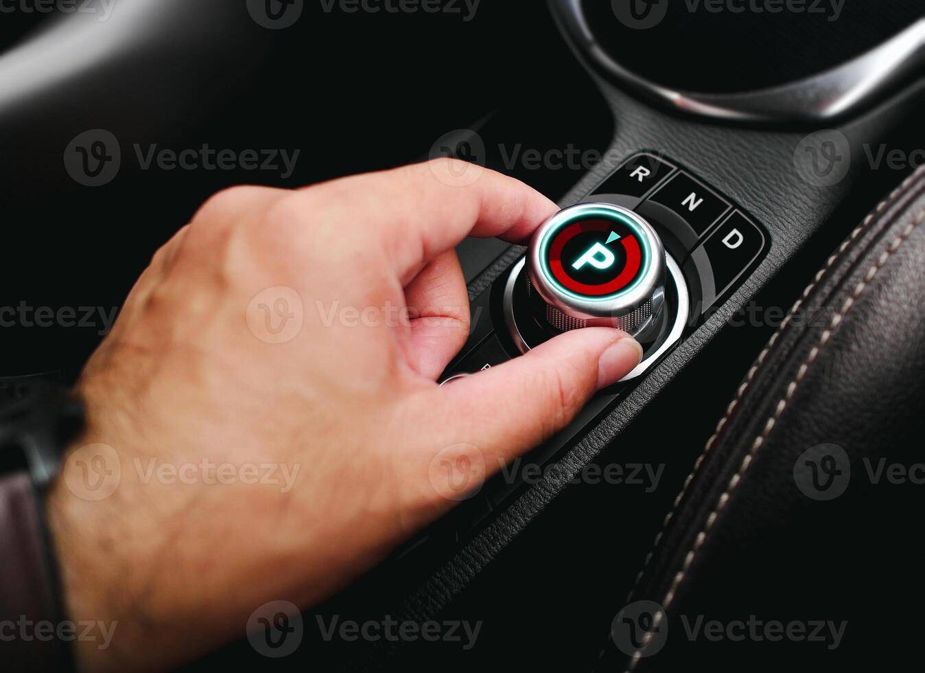 Driver hand turning a rotary gear shift dial on the dashboard of an EV car or electric vehicle , P Parking gear position , electric car technology concept photo