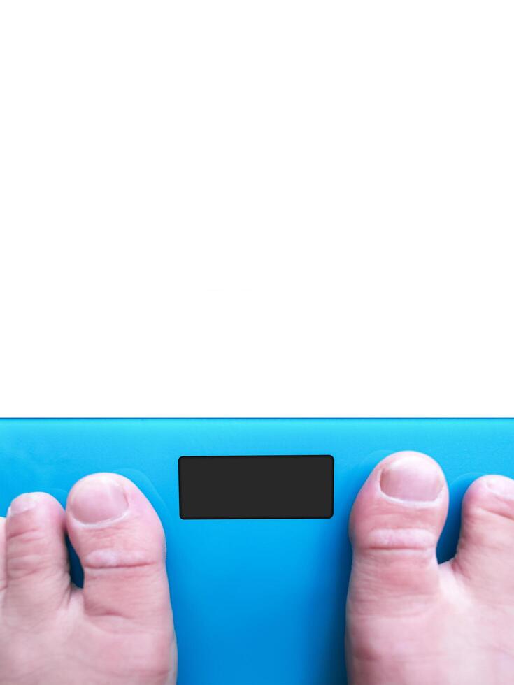 Blank black screen of electronic weighing scale with a barefoot blurred on weight scale , vertical banner with copy space for text on white background , Healthcare concept photo