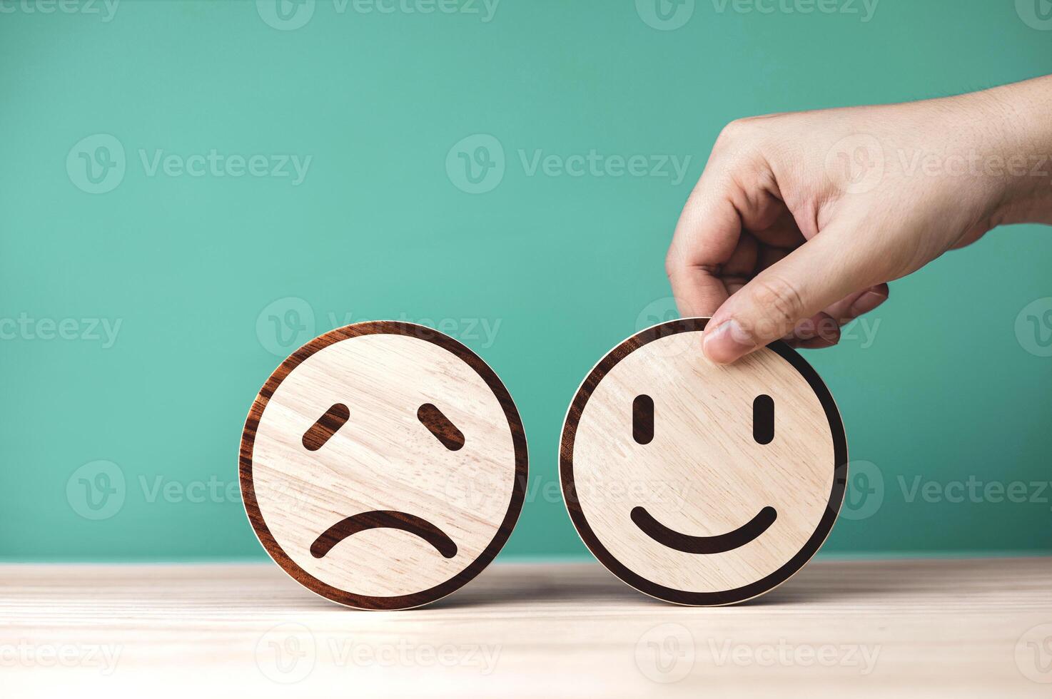 Evaluation level and measurement of quality of customer service. Hand picked wooden circle with most satisfied smiley emoji on green background. photo