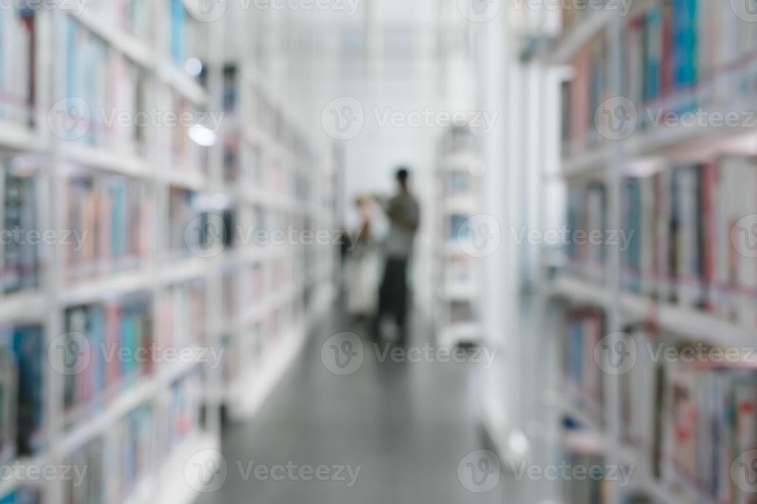 Abstract blurred image of library interior with tall bookshelves background. Man stands in center of quiet library and browsing book photo