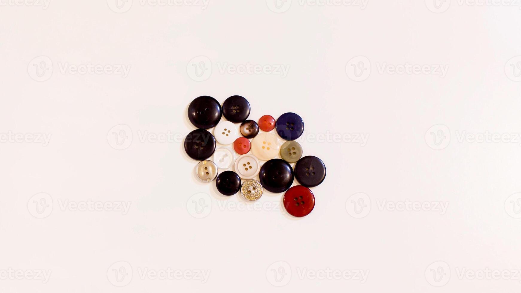 Buttons of various colors and shapes scattered on a white background. photo