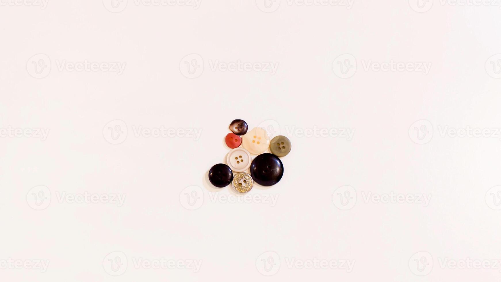 Buttons of various colors and shapes scattered on a white background. photo