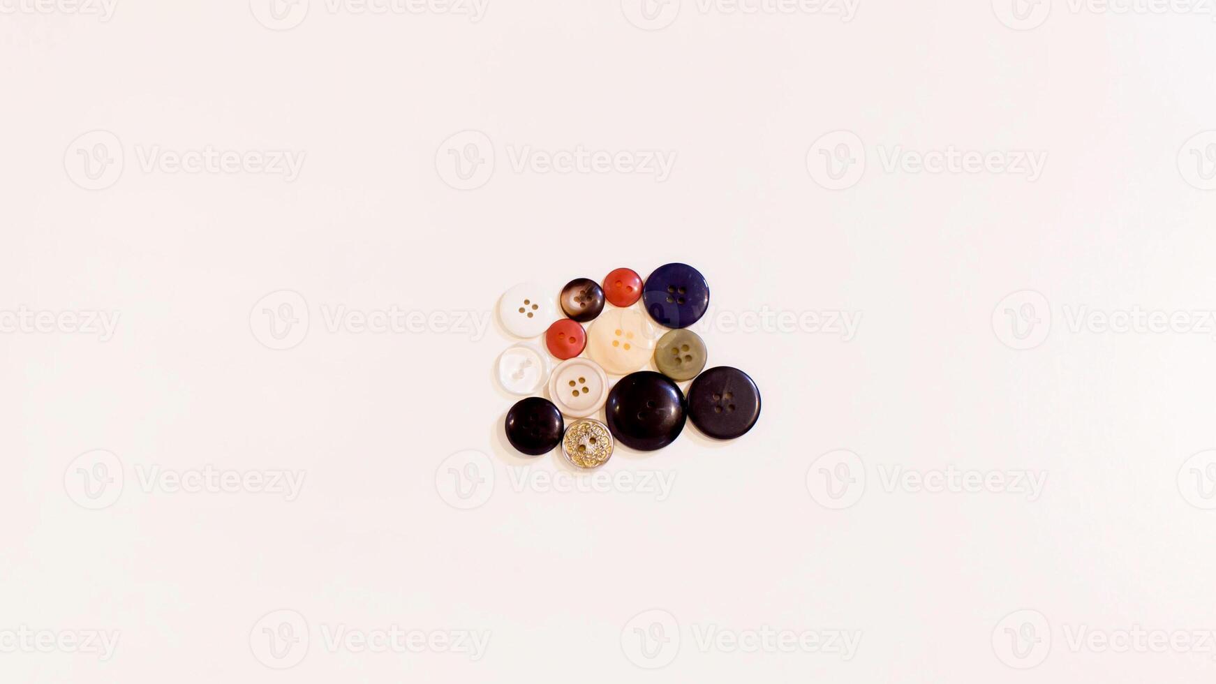 Buttons of various colors and shapes scattered on a white background. photo