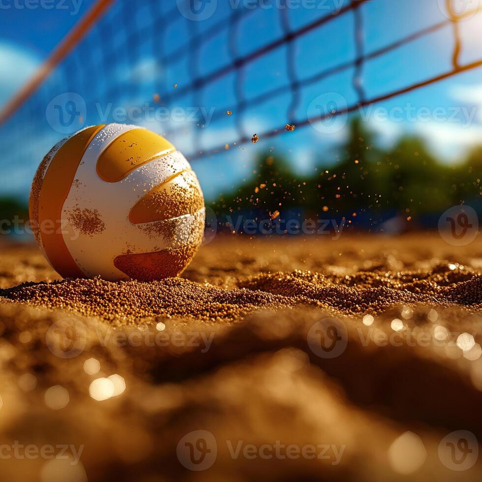 A close-up view of a volleyball resting on sandy court with a net overhead and sun shining in the background. photo