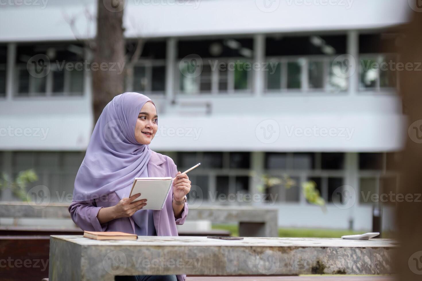 Young Muslim Student in Hijab Studying Outdoors with Tablet at University Campus photo