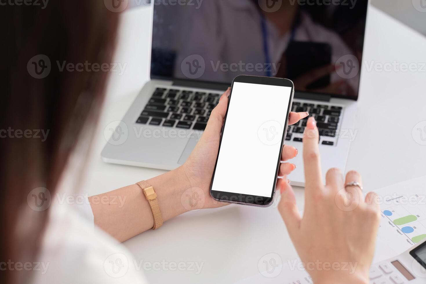 Young Accountant Using Smartphone While Working on Laptop in Modern Office Environment photo