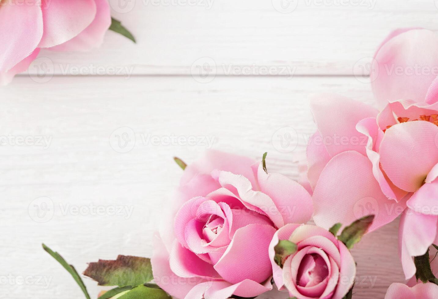 floral frame greeting card. Pink roses on white textured wooden background. Copy space, top view photo