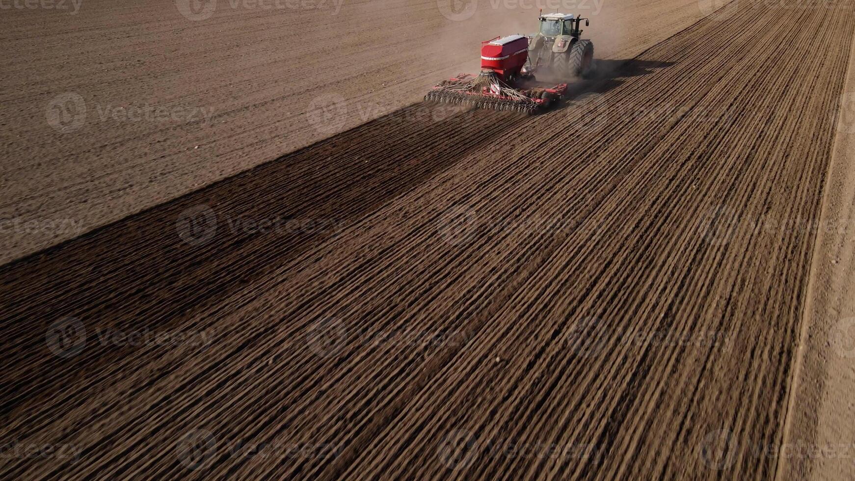 A tractor on the field plows the land, a combine harvester, a view from a drone photo