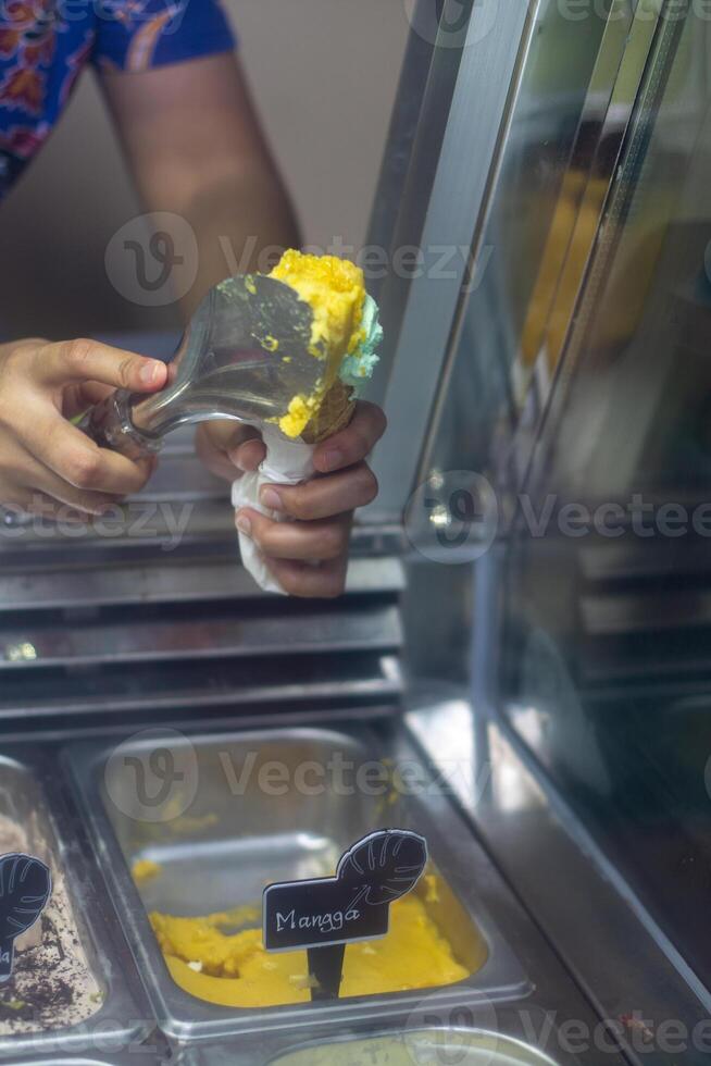 Close up hand of a person scooping ice cream in to a cone with blurred background photo