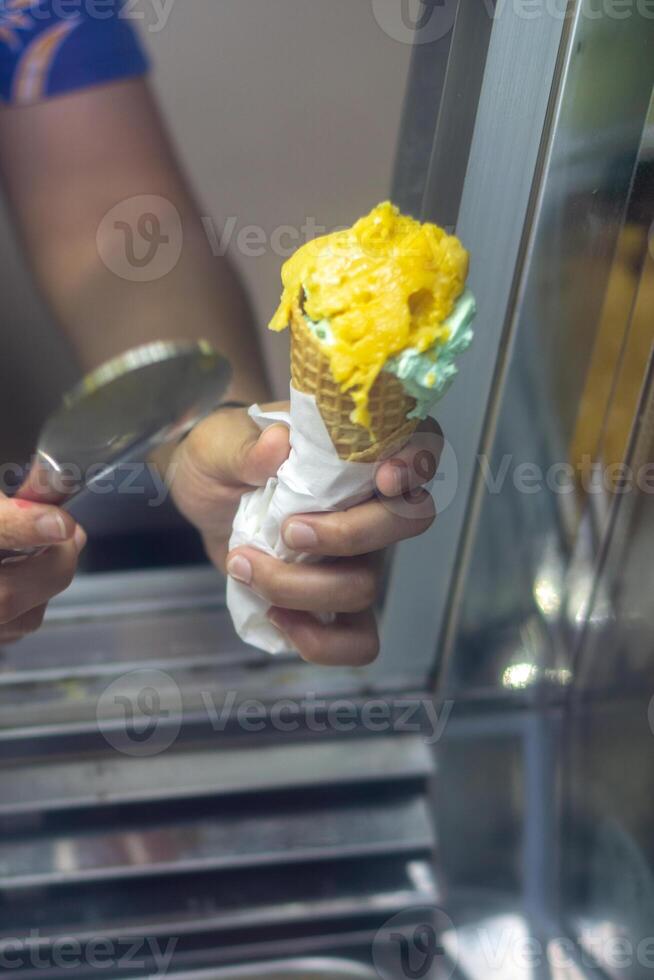 Close up hand of a person scooping ice cream in to a cone with blurred background photo