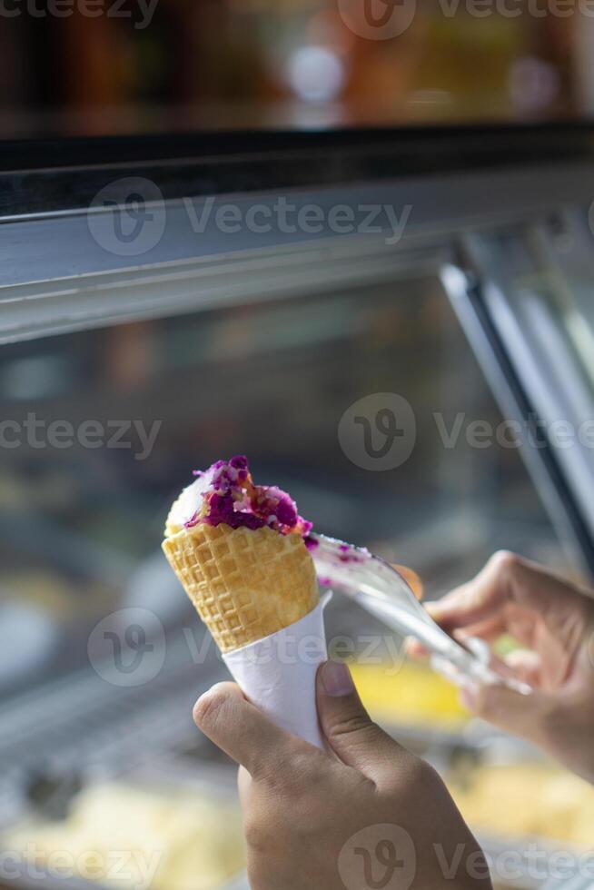Close up hand of a person scooping ice cream in to a cone with blurred background photo