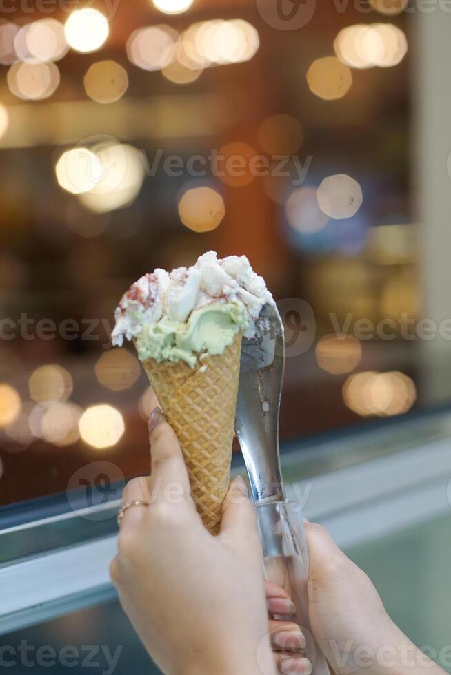 Close up hand of a person holding a cone of ice cream with blurred background photo