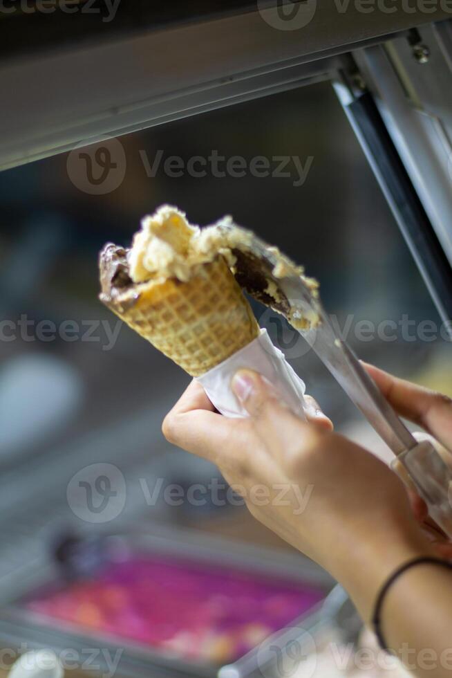 Close up hand of a person scooping ice cream in to a cone with blurred background photo