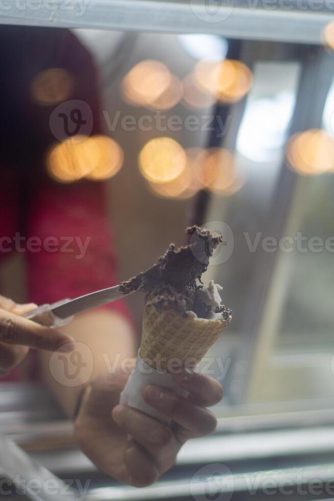 Close up hand of a person scooping ice cream in to a cone with blurred background photo
