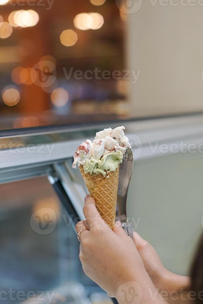 Close up hand of a person holding a cone of ice cream with blurred background photo