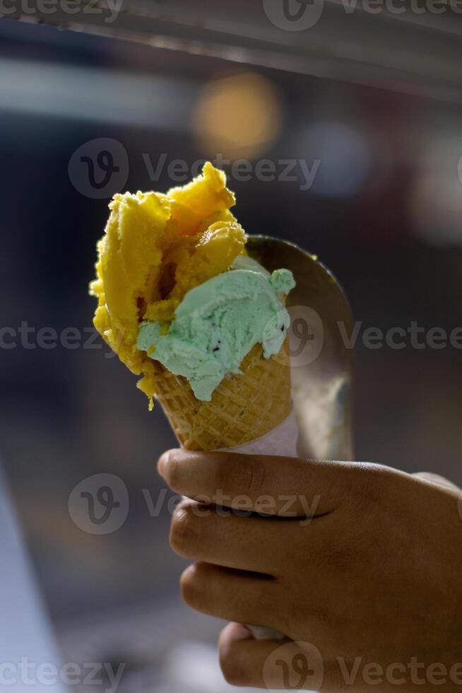 Close up hand of a person holding ice cream cone with blurred background photo