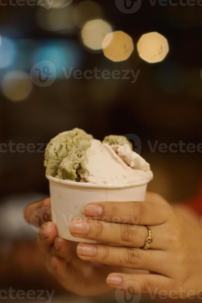 Close up hand of a person holding a cup of ice cream with blurred background photo