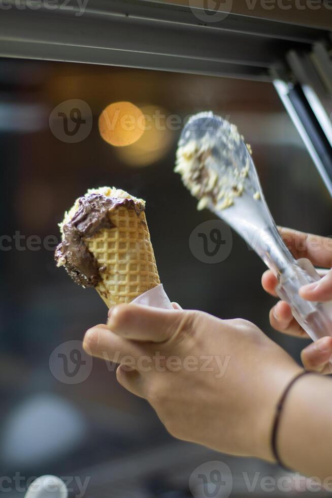 Close up hand of a person holding a cone of ice cream with blurred background photo