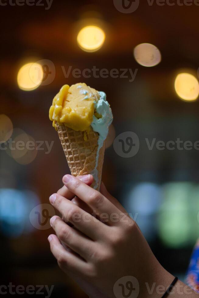 Close up hand of a person holding a cone of ice cream with blurred background photo
