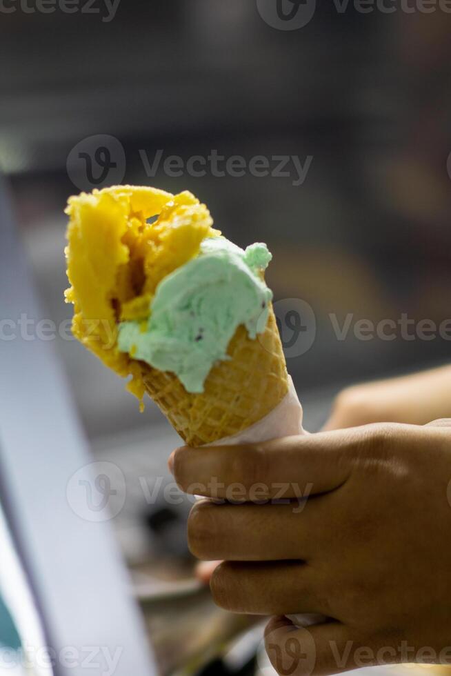 Close up hand of a person holding a cone of ice cream with blurred background photo