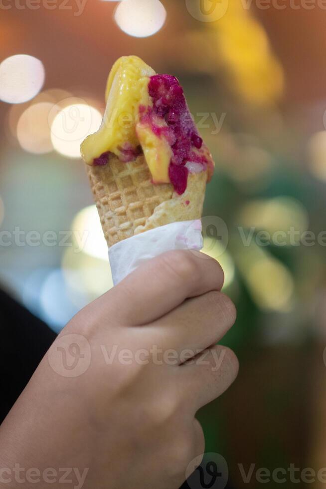Close up hand of a person holding an ice cream cone with blurred background photo