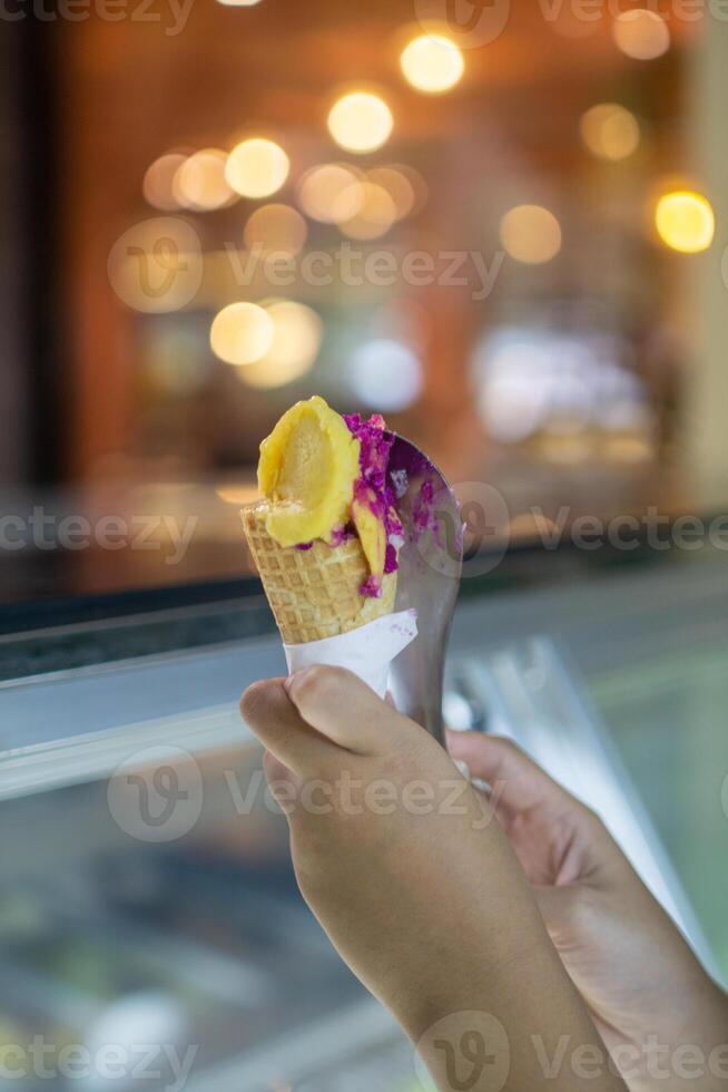 Close up hand of a person holding ice cream cone with blurred background photo