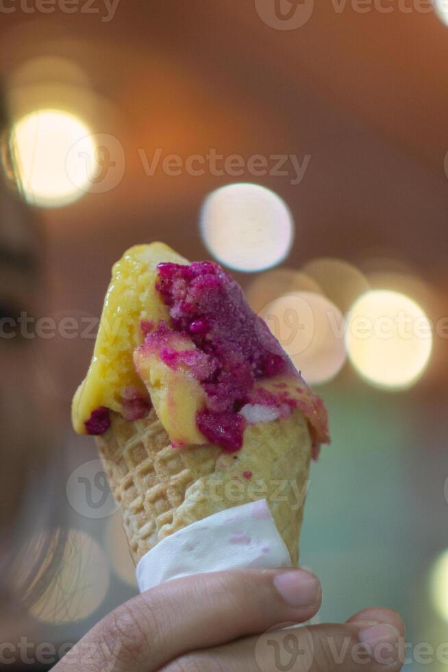 Close up hand of a person holding an ice cream cone with blurred background photo