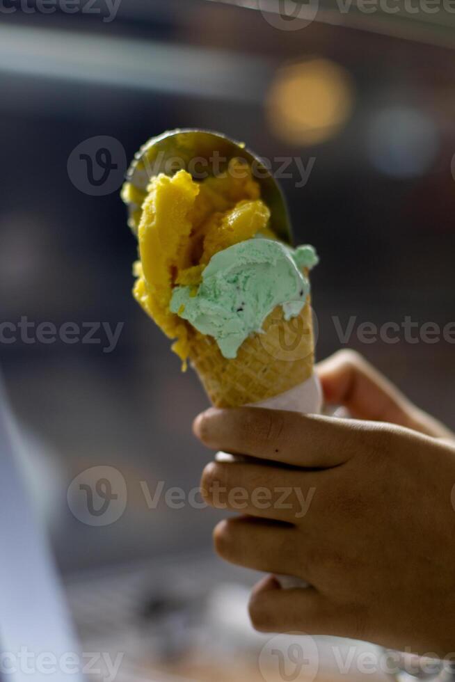 Close up hand of a person holding a cone of ice cream with blurred background photo