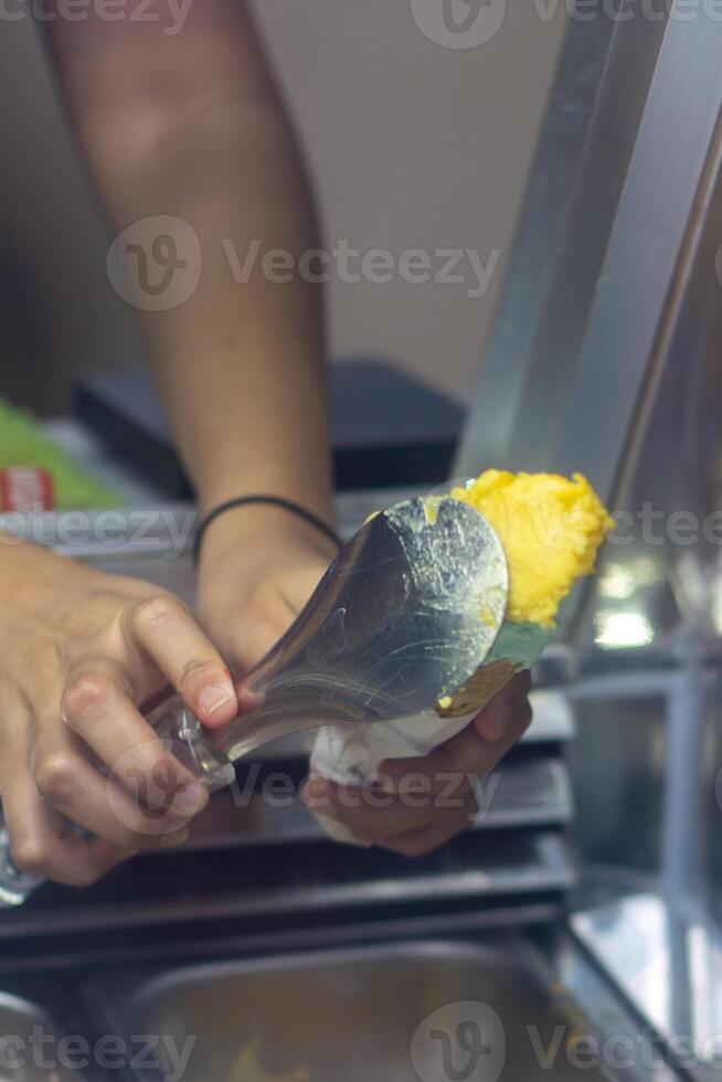 Close up hand of a person scooping ice cream in to a cone with blurred background photo