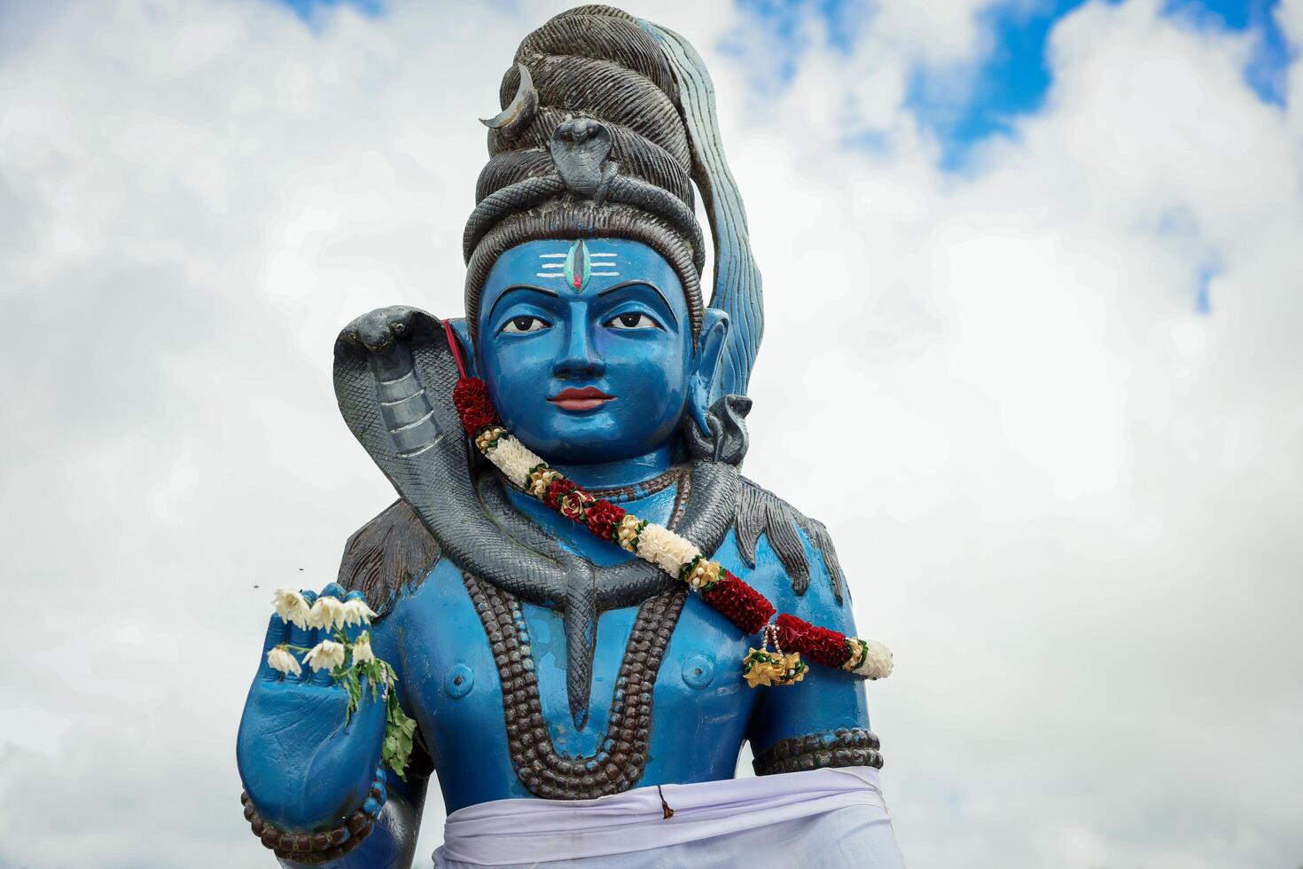 A statue of a man, representing a Hindu deity, holding a snake in his hand. photo
