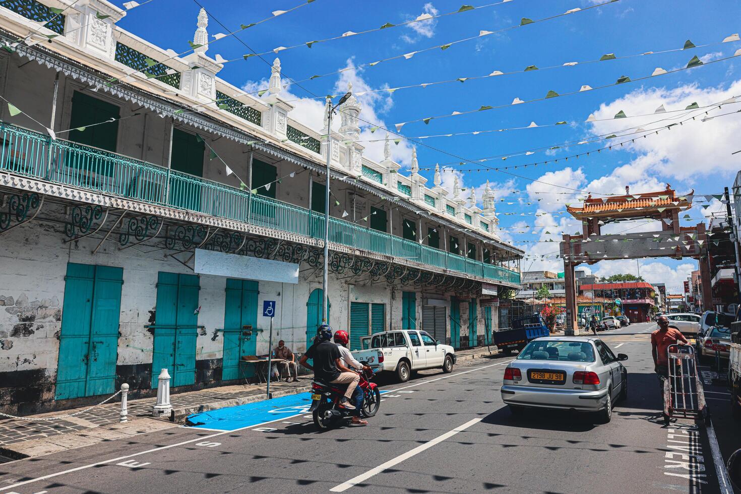 Port Louis, Mauritius - January 14, 2023 - A diverse group of individuals standing in front of a building, located in Port Louis City, Mauritius, with a prominent mosque in the background. photo