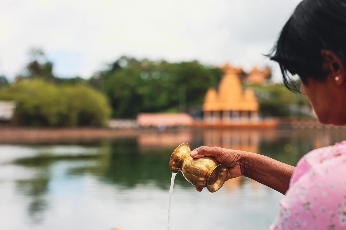 Port Louis, Mauritius - January 12, 2023 - A group of individuals, following Indian Hindu religious traditions, standing next to a body of water in Mauritius. photo