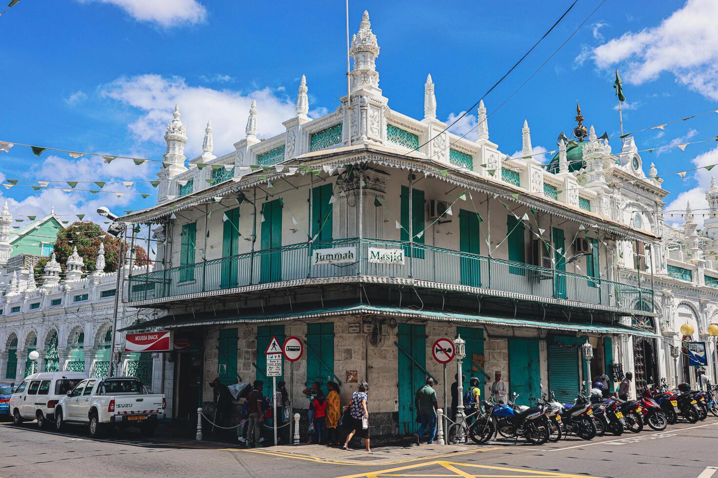 Port Louis, Mauritius - January 14, 2023 - A diverse group of individuals standing in front of a building, located in Port Louis City, Mauritius, with a prominent mosque in the background. photo