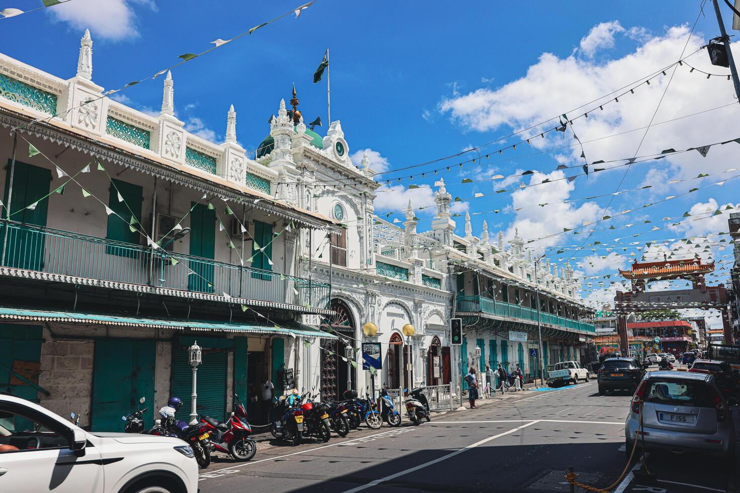 Port Louis, Mauritius - January 14, 2023 - A diverse group of individuals standing in front of a building, located in Port Louis City, Mauritius, with a prominent mosque in the background. photo