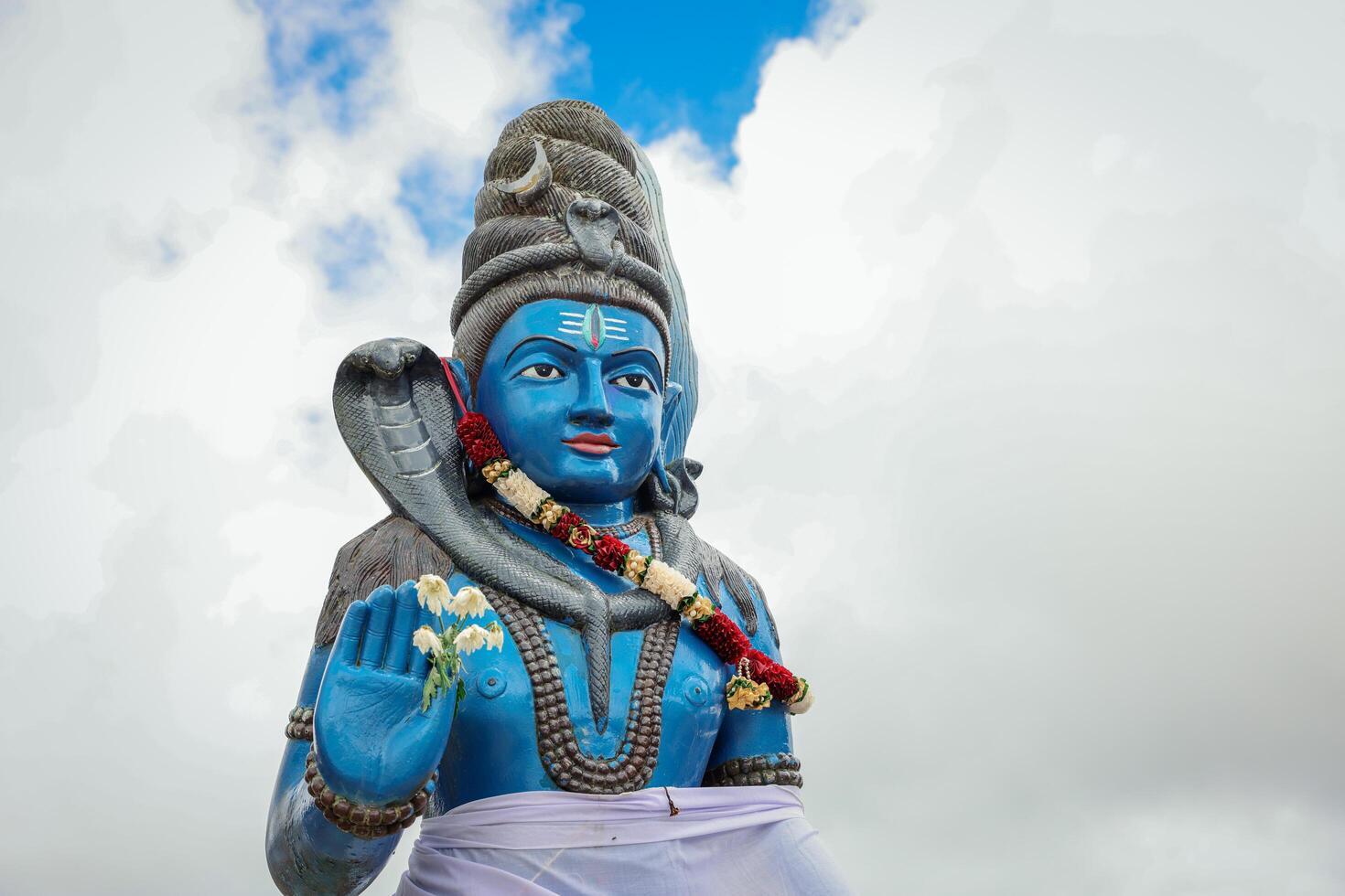 A statue of a man, representing a Hindu deity, holding a snake in his hand. photo