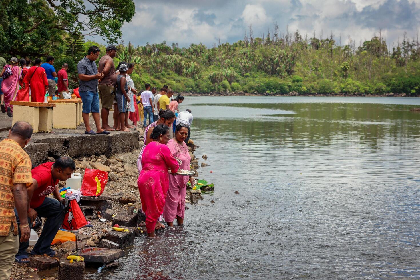 Port Louis, Mauritius - January 12, 2023 - A group of individuals, following Indian Hindu religious traditions, standing next to a body of water in Mauritius. photo