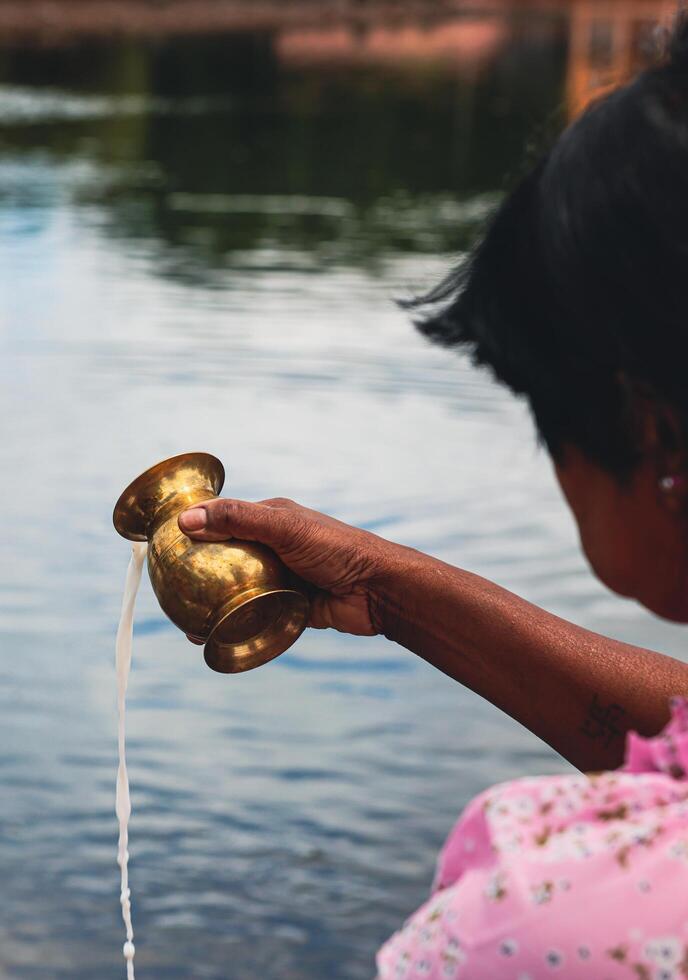 Port Louis, Mauritius - January 12, 2023 - A group of individuals, following Indian Hindu religious traditions, standing next to a body of water in Mauritius. photo
