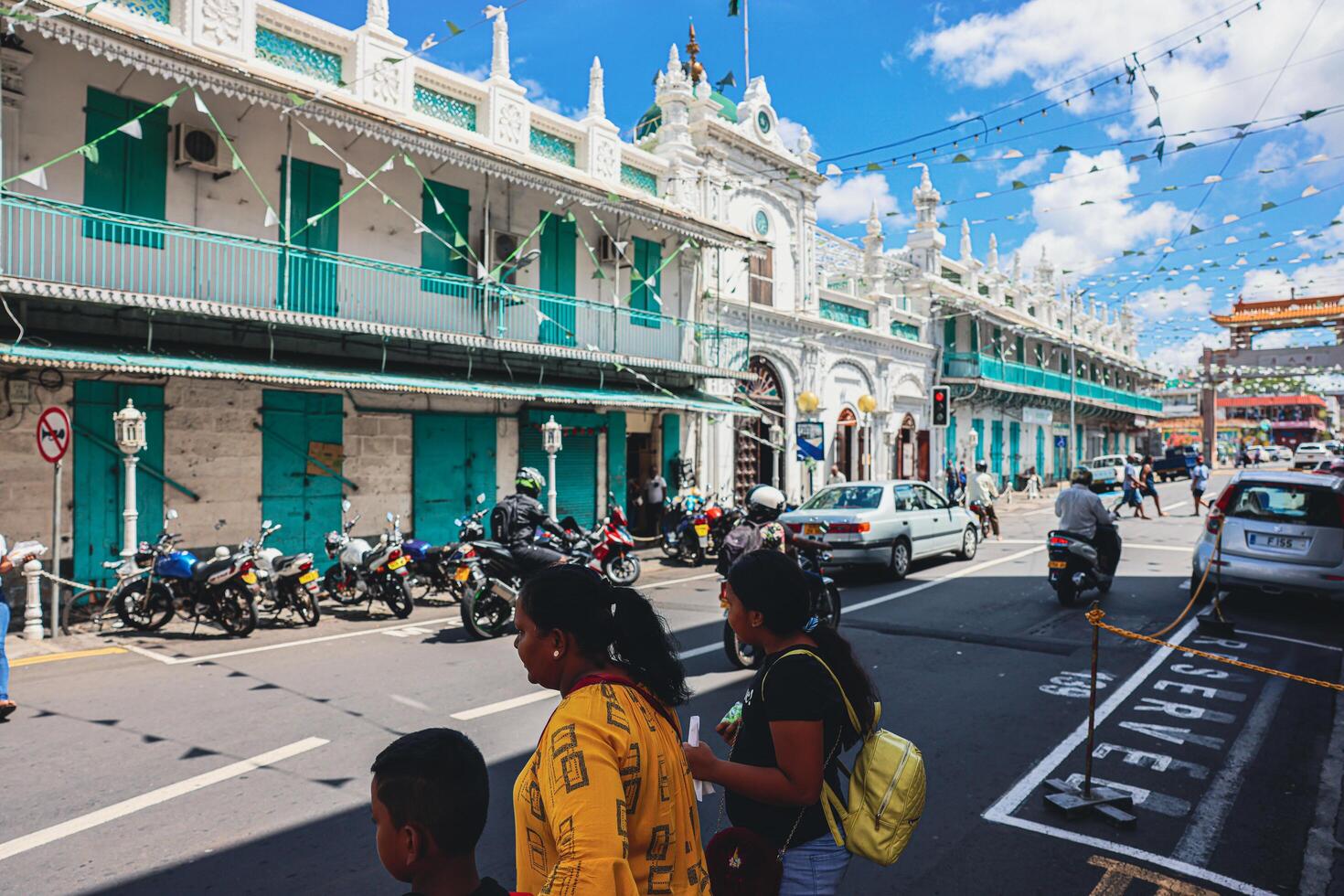 Port Louis, Mauritius - January 14, 2023 - A diverse group of individuals standing in front of a building, located in Port Louis City, Mauritius, with a prominent mosque in the background. photo