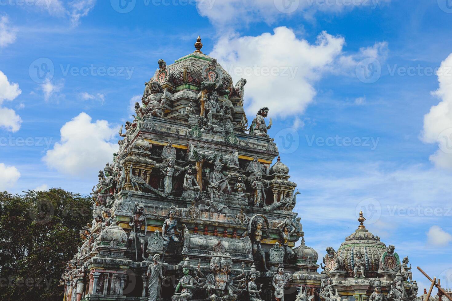 A tall tower featuring intricately carved statues at an Indian temple. photo