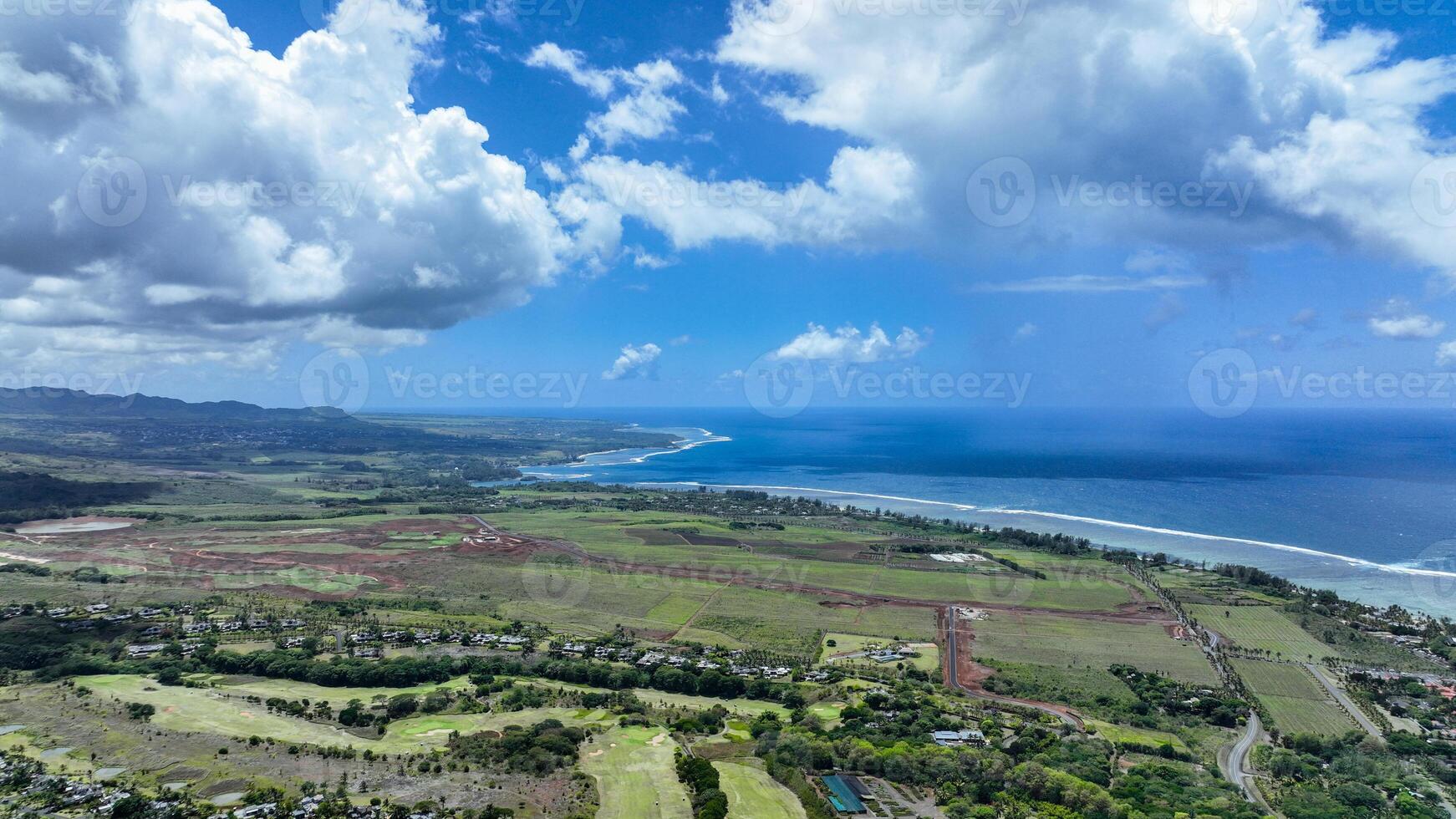 An aerial view captures a winding road as it travels towards the ocean, showcasing the interaction between man-made infrastructure and the natural environment. photo