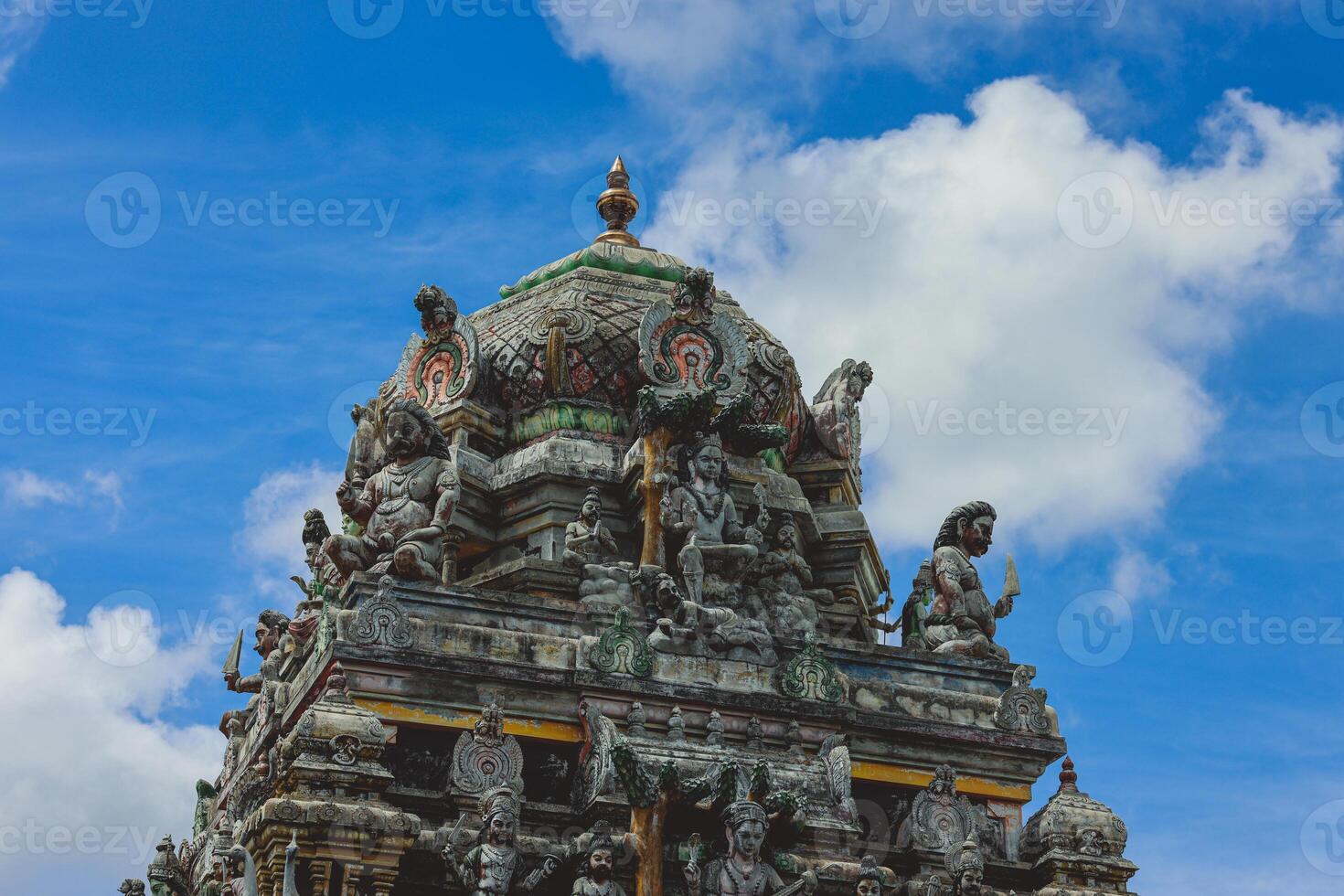 A tall tower featuring intricately carved statues at an Indian temple. photo