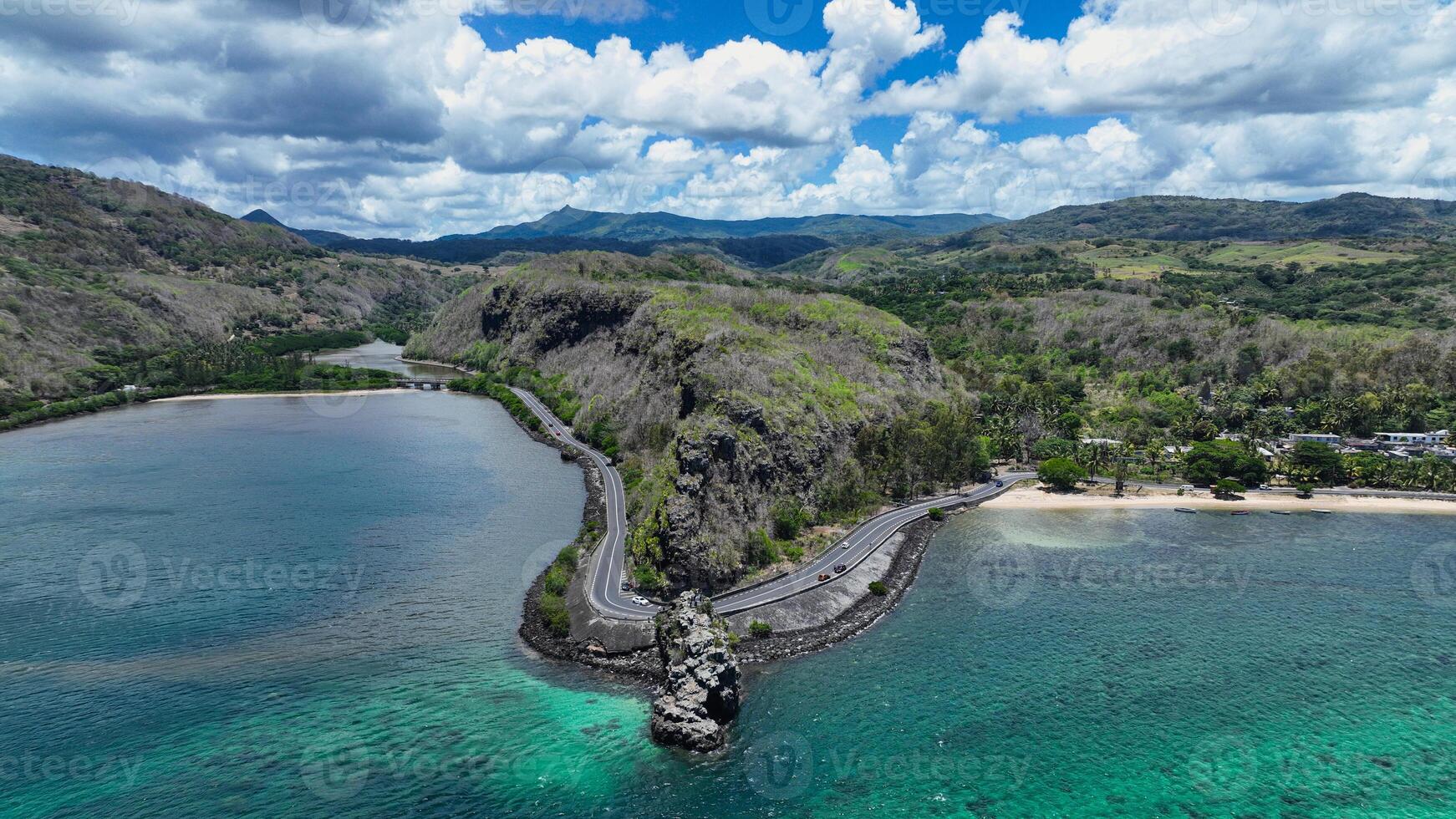 An aerial view captures a winding road as it travels towards the ocean, showcasing the interaction between man-made infrastructure and the natural environment. photo