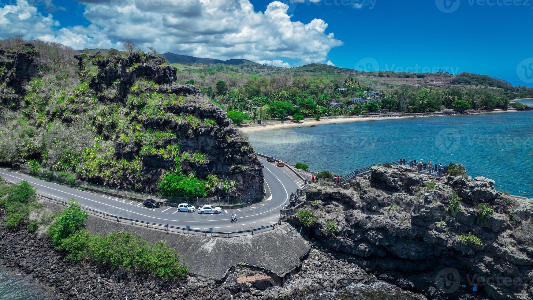 An aerial view captures a winding road as it travels towards the ocean, showcasing the interaction between man-made infrastructure and the natural environment. photo