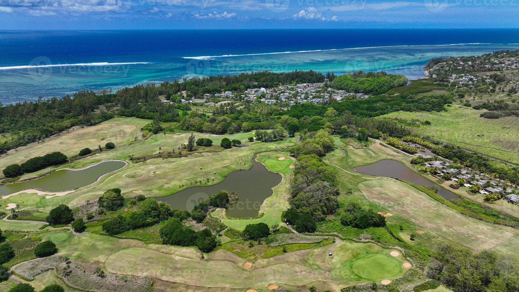 This aerial photograph showcases a golf course in Mauritius, with the fairways and greens beautifully laid out amidst a surrounding expanse of water. photo