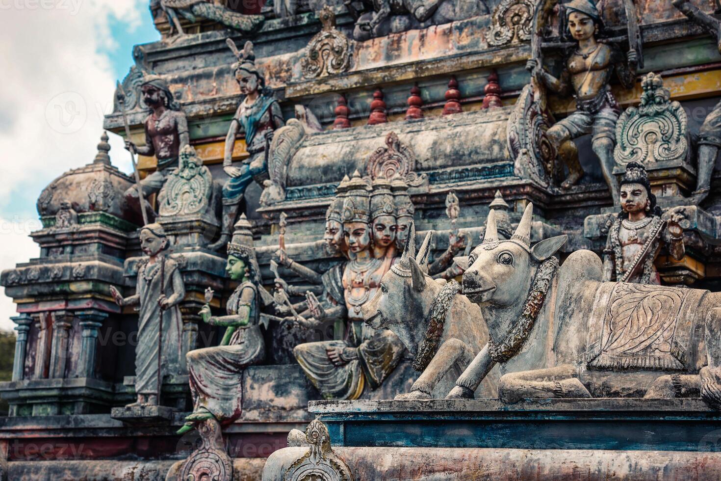 A tall tower featuring intricately carved statues at an Indian temple. photo