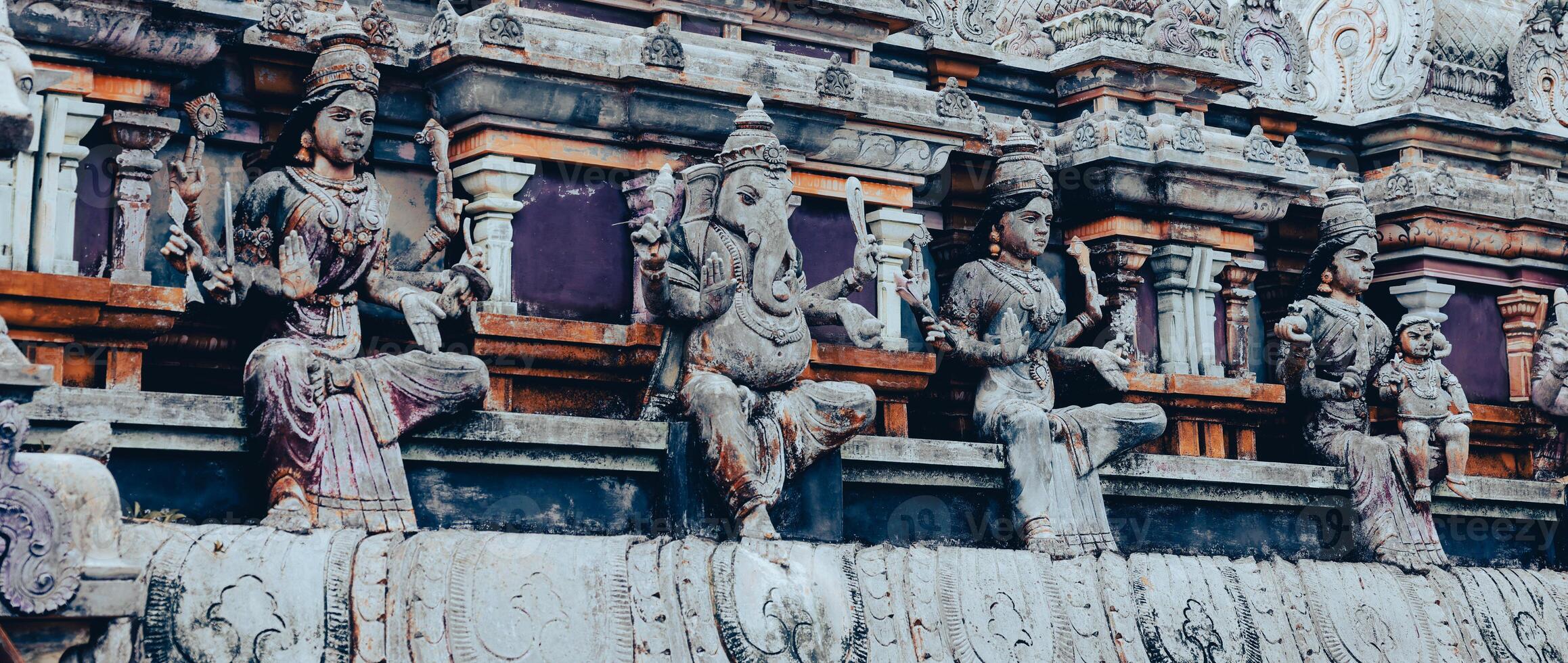 A tall tower featuring intricately carved statues at an Indian temple. photo