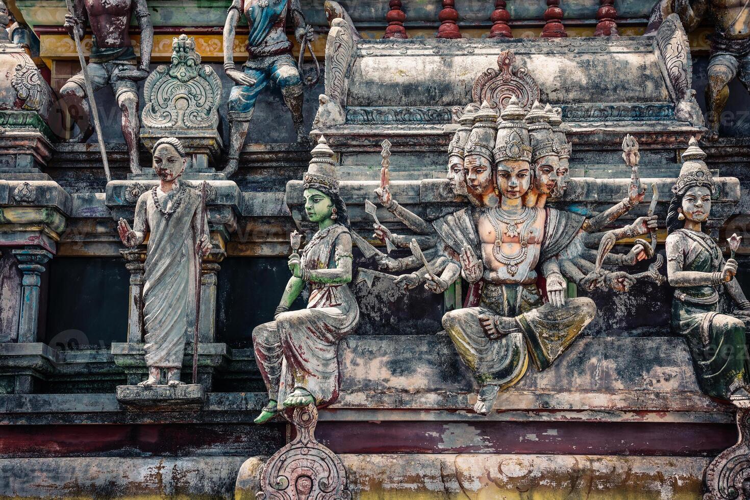 A tall tower featuring intricately carved statues at an Indian temple. photo